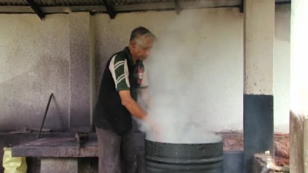 Muž omývá batikování textilu v horké vodě v továrně v Kandy, Srí Lanka. — Stock video