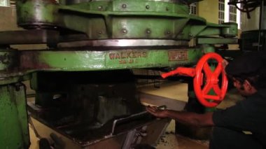 Adam eski çay kesme makinesi ile Nuwara Eliya, Sri Lanka çay fabrikasında çalışıyor.