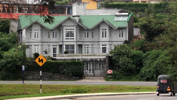 Bil passerar vägen med den traditionella koloniala byggnad på bakgrunden i Nuwara Eliya, Sri Lanka. — Stockvideo