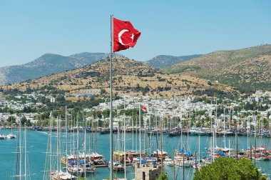 Bodrum, Türkiye'de bir tepe üzerinde sallayarak bayrak direği, Türk ulusal bayrak ile marina için görüntüleyin.
