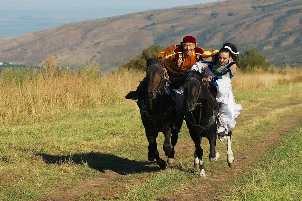 Människor bär nationella klänningar rida på landsbygden, Almaty, Kazakstan. — Stockfoto