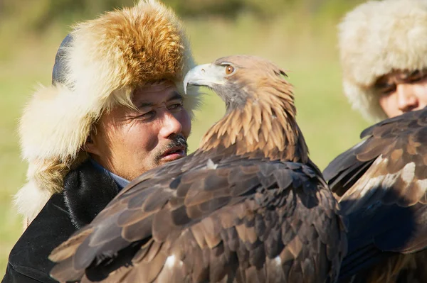 Portrait of unidentified Kazakh hunters holding golden eagles (Aquila chrysaetos), circa Almaty, Kazakhstan. — Stock Photo, Image