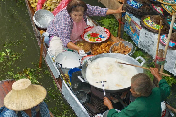 Menschen verkaufen Lebensmittel von Booten auf dem schwimmenden Markt in Damnoen Saduak, Thailand. — Stockfoto