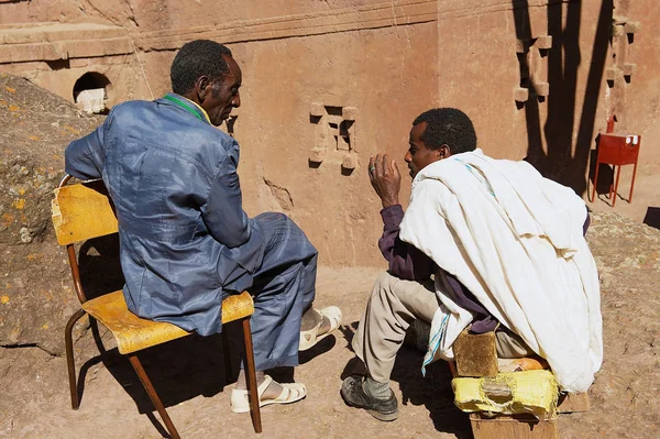 Pilgrims talk with the monolithic rock-hewn church at the background in Lalibela, Ethiopia. — Stock Photo, Image