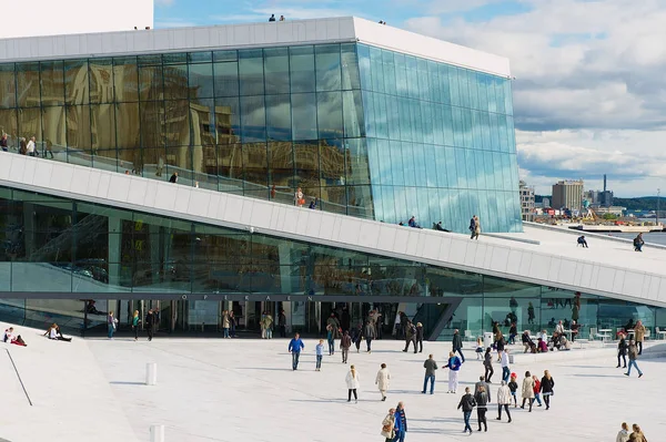 People walk in front of the modern National Oslo Opera House building in Oslo, Norway. — Stock Photo, Image