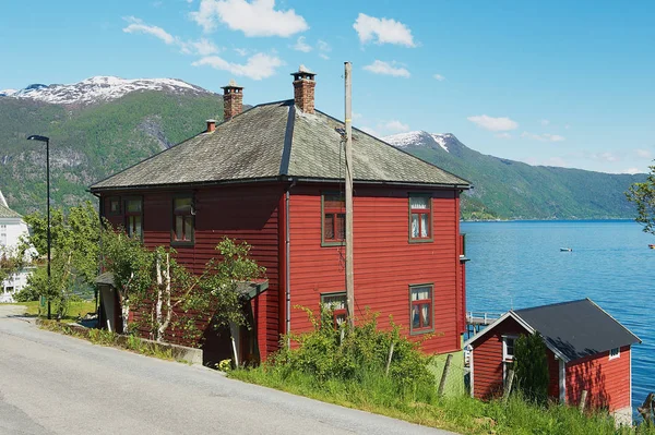 Met het oog op het traditionele rood geschilderde Noorse huis met Sognefjord op de achtergrond in Balestrand, Noorwegen. — Stockfoto