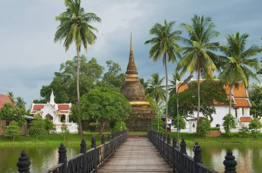 Wat Traphang tanga ile köprü için ön planda Sukhothai, Thailand bir gölette üzerinde görüntüleyin.