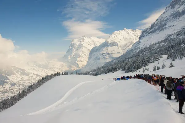 Ludzie cieszyć się widokiem na góry czekają w kolejce do wzięcia udziału w rocznej wyścigu Horn-sanki z Ried do Grund w Grindelwald, Switzerland. — Zdjęcie stockowe