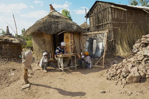 LALIBELA, ETHIOPIA - JANUARY 27, 2010: Unidentified people paint and read at the house entrance in Lalibela, Ethiopia. Ethiopia has one of the highest levels of illiteracy in the world.