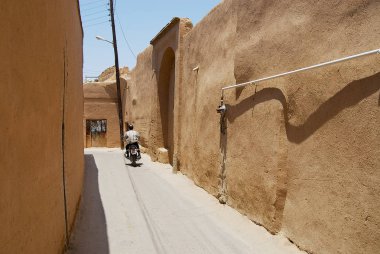 Yazd, Iran - Haziran 17, 2007: Kimliği belirsiz Yezd, İran'ın tarihi bölümünde kil kaplı duvarlı dar sokak tarafından Motosiklet sürmek.