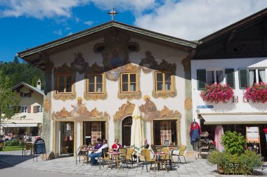 Mittenwald, Almanya - 01 Eylül 2010: Kimliği belirsiz kişi geleneksel Bavyera boyalı house adlı arka planda Mittenwald, Almanya ile küçük sokak café'de rahatlayın.