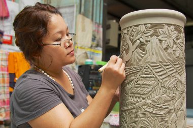 Kuching, Malezya - 27 Ağustos 2009: Kimliği belirsiz bir kadın kesim geleneksel tribal dövme motifleri dekorasyon ham kaolin bir atölyede Kuching, Malezya. 