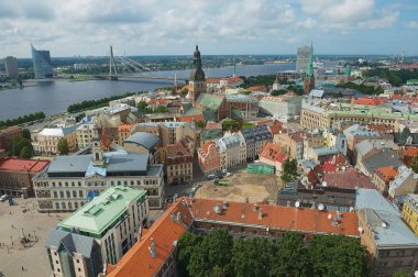 Riga, Letonya - 04 Ağustos 2009: Riga şehrindeki St. Peter kilisesinden eski şehir binalarının ve Daugava nehri karşısındaki köprünün panoraması.
