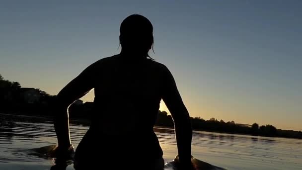 Kobieta gra na wody o zachodzie słońca. Zwolnionym tempie. — Wideo stockowe