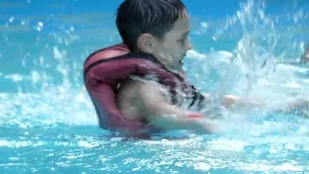 Pojken har roligt i poolen. Han gör stänk hans händer i Slow Motion. — Stockvideo