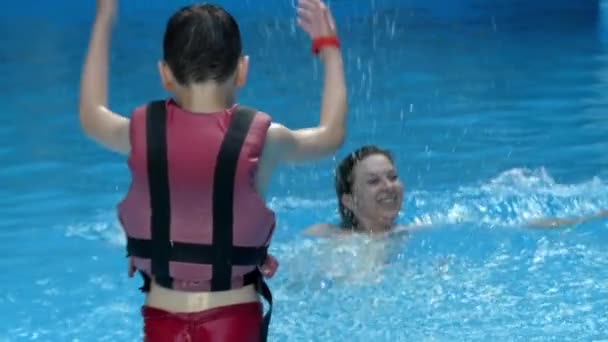 Malého chlapce hrát se svou matkou v bazénu v pomalém pohybu. — Stock video