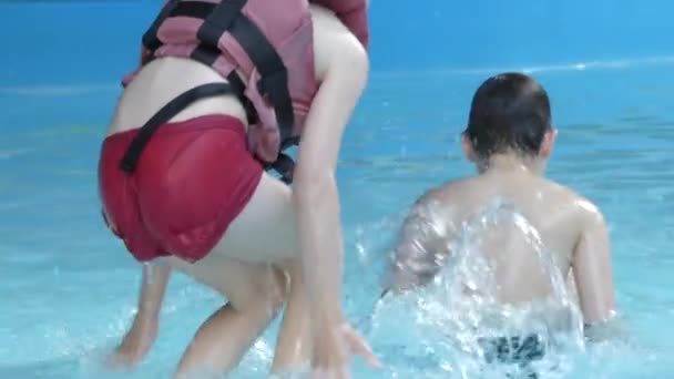 A kis fiúk fröccsenése a medencében. Lassú mozgás. — Stock videók
