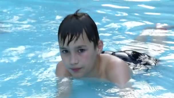 小さな男の子がプールで横になっている水の休憩します。スローモーション. — ストック動画