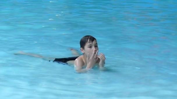 Liten pojke vila i vattnet ligga i poolen. Slow Motion. — Stockvideo