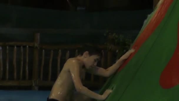 Jongen klimmen naar de Top van de glijbaan in het Aqua Park. en daarna naar beneden. — Stockvideo