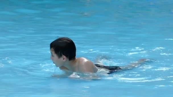 Menino descansando na água deitado na piscina. Movimento lento . — Vídeo de Stock