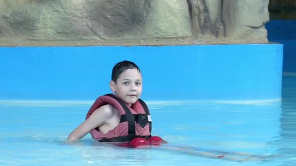 Menino descansando na água deitado na piscina. Movimento lento . — Vídeo de Stock