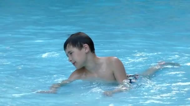 Menino descansando na água deitado na piscina. Movimento lento . — Vídeo de Stock