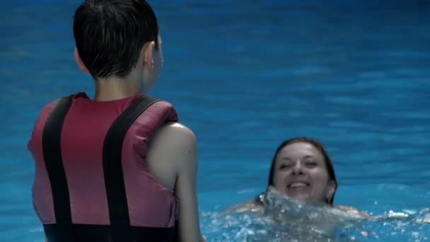 Niñito jugando con su madre en la piscina a cámara lenta . — Vídeo de stock