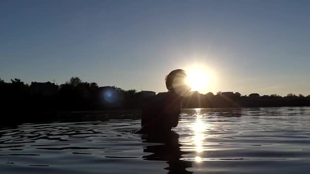 Mãos de mulher fazem respingo na água em câmera lenta durante o pôr do sol . — Vídeo de Stock