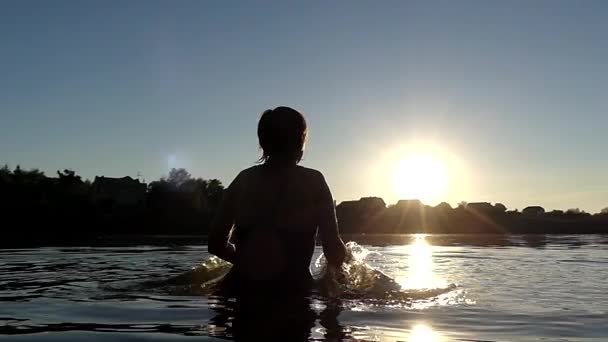 Las manos de la mujer hacen chapoteo en el agua en cámara lenta durante el atardecer . — Vídeos de Stock