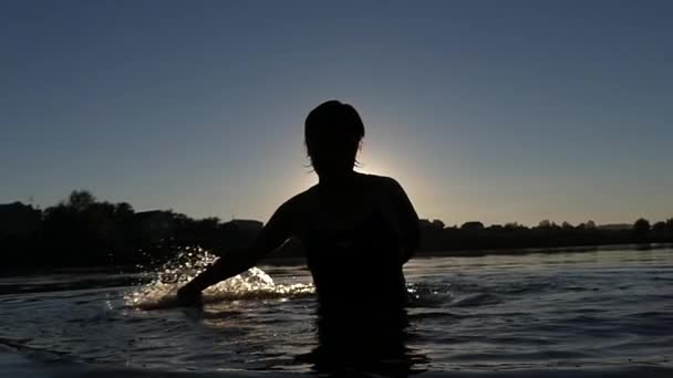 Las manos de la mujer hacen chapoteo en el agua en cámara lenta durante el atardecer . — Vídeo de stock