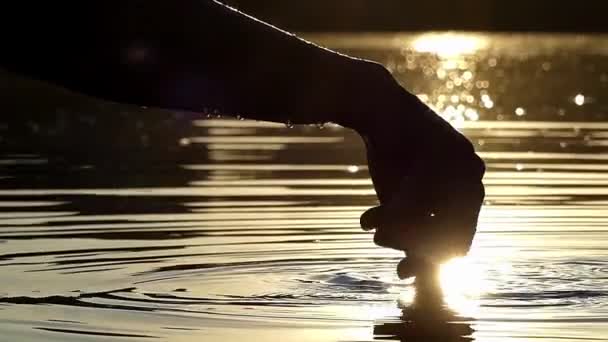 Dedos brincam com água em câmera lenta ao pôr do sol . — Vídeo de Stock