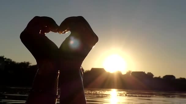 Les mains de la femme montrent le cœur au coucher du soleil au ralenti . — Video