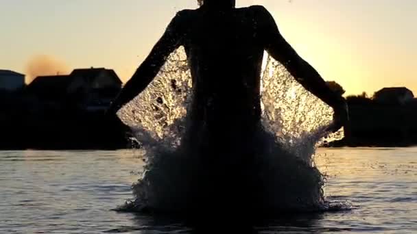 Springt der Kerl bei Sonnenuntergang in Zeitlupe aus dem Wasser. Sieg. — Stockvideo