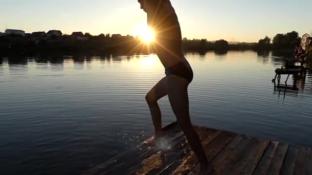 Muž skočí Salto do vody. Pomalý pohyb při západu slunce. — Stock video