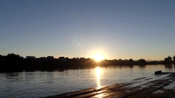 Man hoppa i vattnet vid solnedgången från bron. — Stockvideo