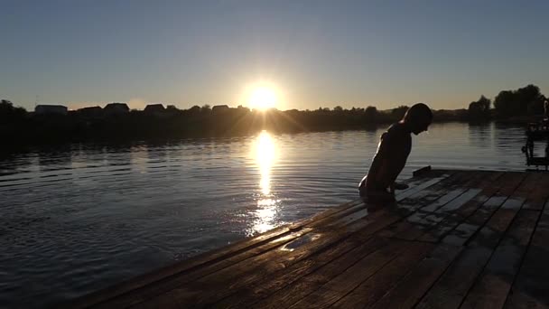 Un hombre sale del agua en cámara lenta. Puesta de sol . — Vídeos de Stock