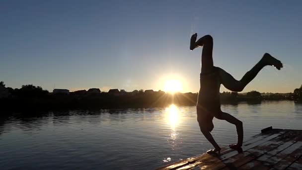 Man Make Handstand e saltare in acqua. l'azione al tramonto al rallentatore . — Video Stock
