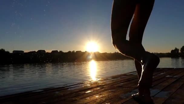 Man skoki do jeziora w zwolnionym tempie o zachodzie słońca. — Wideo stockowe