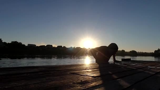 Il grimpe sur un pont en bois près du lac. Mouvement lent . — Video