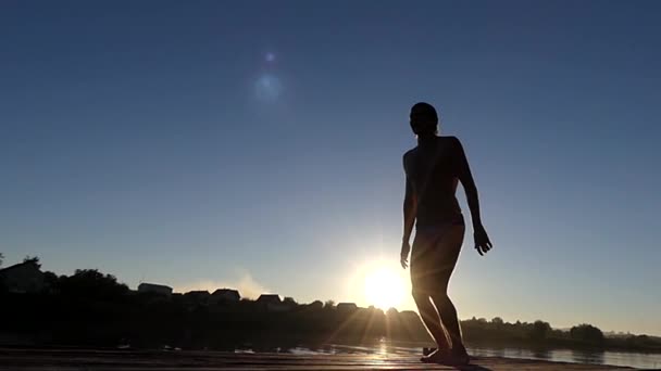 Mann auf der Brücke springt bei Sonnenuntergang in Zeitlupe in den Himmel. — Stockvideo