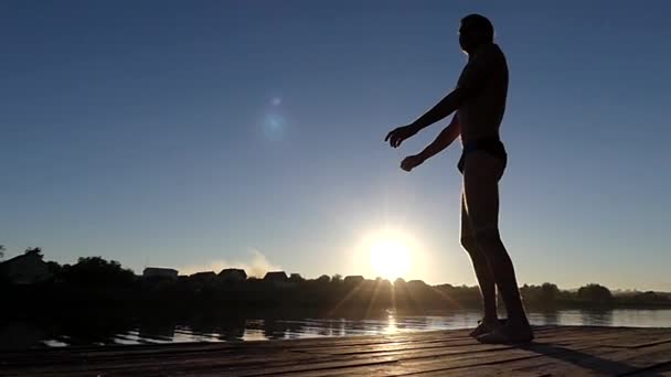 Profi úszó gyakorlatok, hogy kezdete előtt. a művelet a tavon naplementekor. — Stock videók