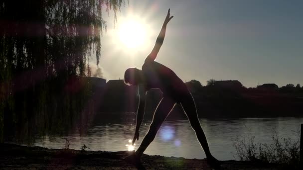 Yoga Pose üçgen üzerinde duran adam silüeti. Göl günbatımı. — Stok video