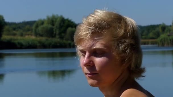 Visage Blonde Gros plan Apprécie la vie. il Souriant et heureux avec les yeux serrés. l'Action sur le lac . — Video