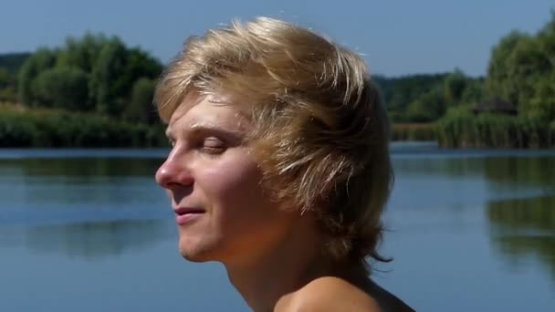 Ansikte Blondin närbild njuter av livet. han leende och glad med nära ögonen. Åtgärden på sjön. — Stockvideo