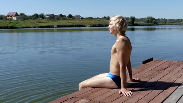 Blonde Man zit op de houten brug. Vrijheid. — Stockvideo