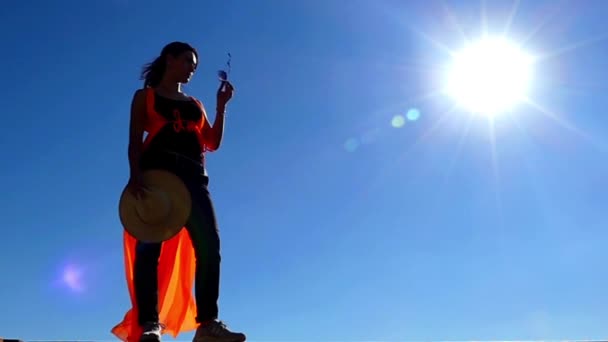 Mooi model staande in de zon en zet zonnebrillen in slow motion. — Stockvideo