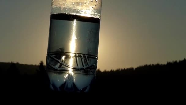 Bouteille d'eau au coucher du soleil dans la lumière du soleil. Mouvement lent . — Video