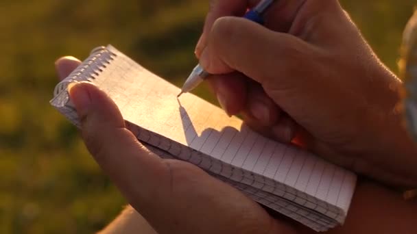 A caneta escreve no papel do bloco de notas. Luz solar . — Vídeo de Stock