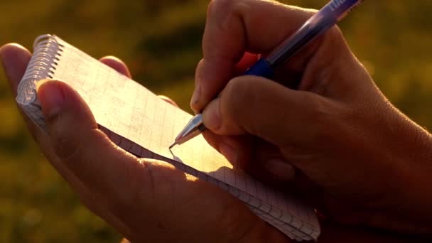 A caneta escreve no papel do bloco de notas. Luz solar . — Vídeo de Stock